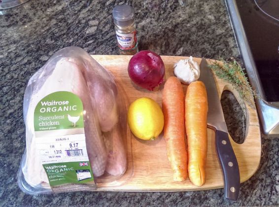 Ingredients for making John style roast chicken, consisting of lemon, pepper, carrots, red onion and garlic